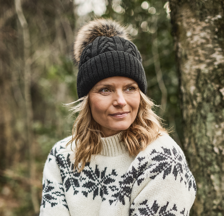 Strikhue MARIKA sort med pompon af finsk vaskebjørn